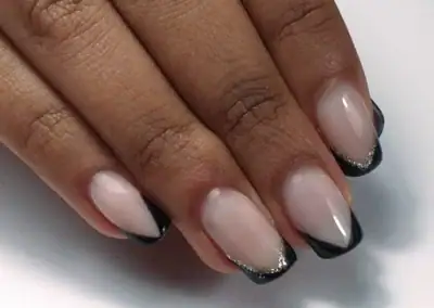 Ongles avec French manucure élégante et détails pailletés noirs et argentés.